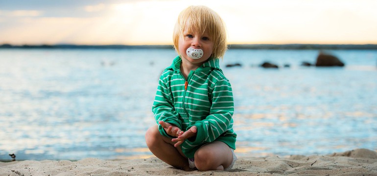 En liten kille sitter på stranden